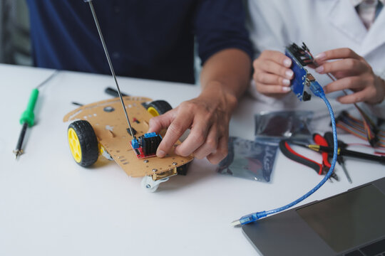 Engineers assembling diy robot car with electronic components in laboratory