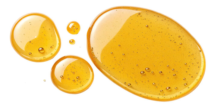 Golden honey droplets on a white background reflecting light and texture