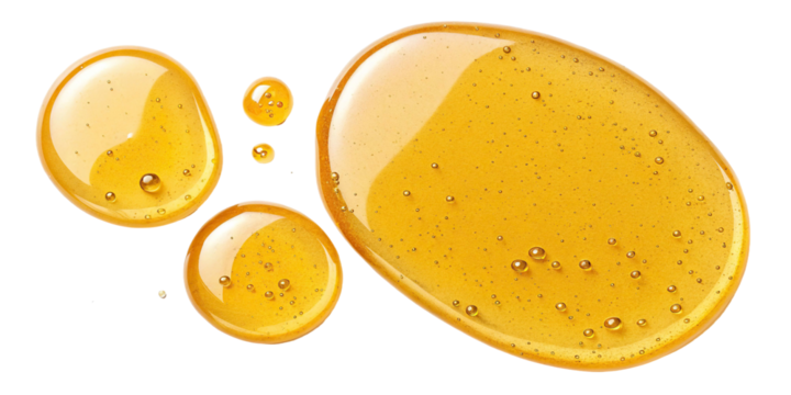 Golden honey droplets on a white background reflecting light and texture