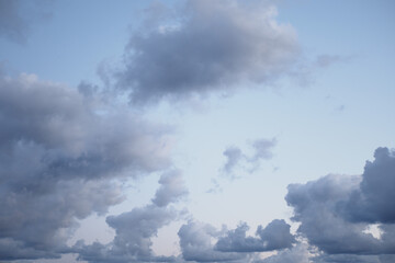 Soft gray clouds drift across a serene blue sky at dusk
