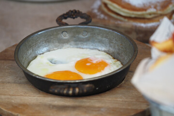 Sunny side up eggs served in a rustic pan at breakfast table