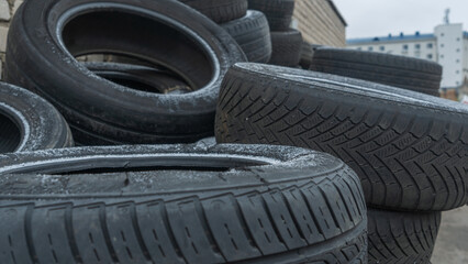 Obraz premium Close-up view of discarded old car tires outdoors, showcasing a pile of used tires ready for recycling. Highlighting environmental concerns and rubber waste management