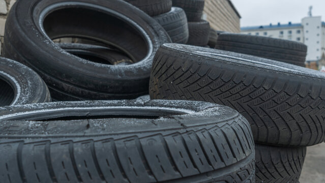 Close-up view of discarded old car tires outdoors, showcasing a pile of used tires ready for recycling. Highlighting environmental concerns and rubber waste management