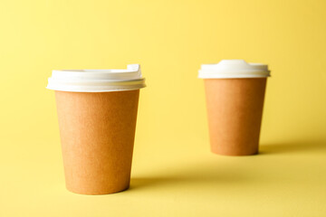 Paper cups on yellow background, selective focus. Mockup for design