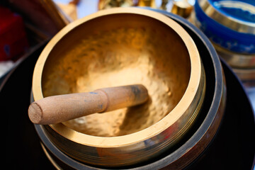 Close-up shot of a golden Tibetan singing bowl with a wooden mallet
