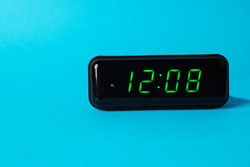 Digital alarm clock showing 12:08 o'clock on light blue background, space for text