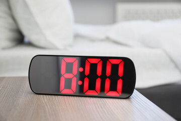 Digital alarm clock showing 8:00 o'clock on bedside table indoors