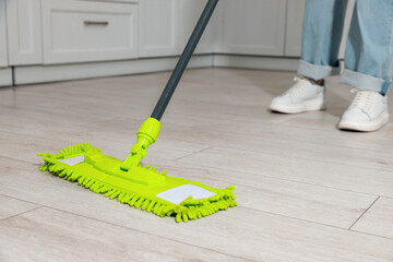 Woman cleaning floor with mop at home, closeup