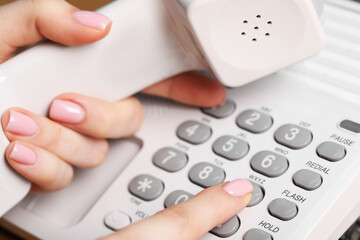 Woman dialing number on landline telephone, closeup