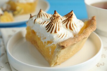 Piece of delicious pie with browned meringue on light blue table, closeup