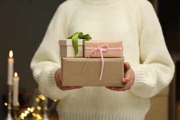 Woman with parcel and gift boxes indoors, closeup