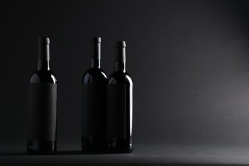 Bottles of wine on black background, space for text
