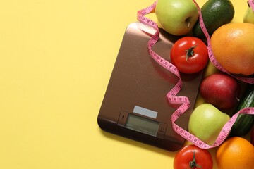Electronic kitchen scale, measuring tape and products on yellow background, flat lay. Space for text