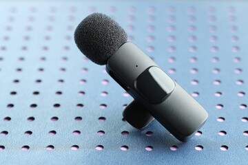 Lavalier microphone on blue notebook, closeup. Audio equipment