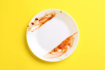 One dirty plate on yellow background, top view