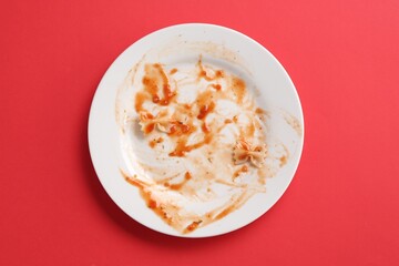 Dirty plate on red background, top view