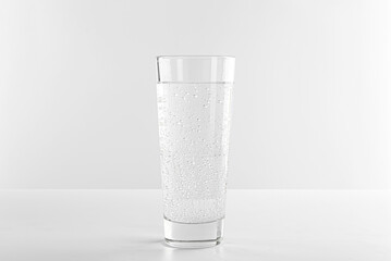 Refreshing soda water in glass on white table against light background