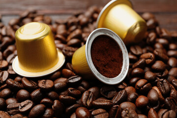 Coffee capsules and beans on wooden table, closeup