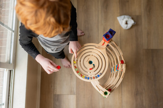 From above view of young boy playing with wooden block marble run
