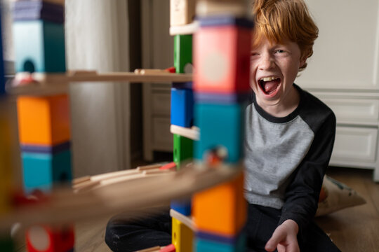 Young boy laughing and playing with his block marble run building set