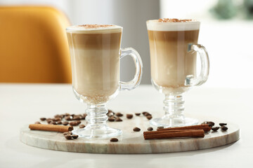 Tasty latte macchiato, coffee beans and cinnamon sticks on white table, closeup