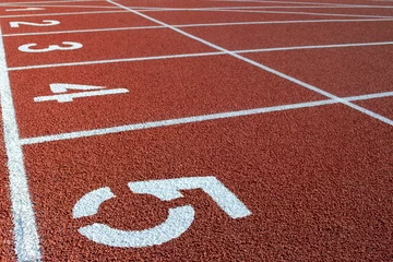 Fototapeten Numbers on the red running track of the garden. White stripes and numbers on the red track, close-up. Starting field for sprint at the stadium. Running track at the stadium for competitions. © aneriksson