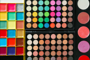 Face paints and makeup products as background, top view
