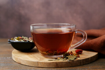 Delicious herbal tea and dry leaves on wooden table, closeup