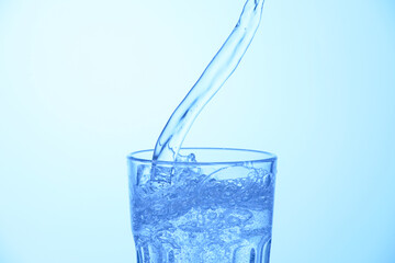 Pouring soda water into glass on light blue background, closeup