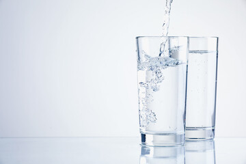 Pouring refreshing soda water into glasses on light background, closeup. Space for text