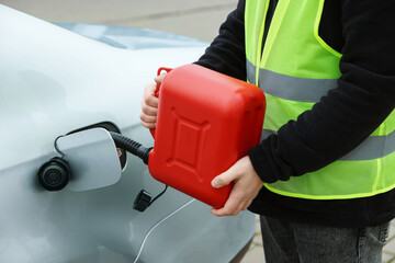 Man with canister refueling car outdoors, closeup