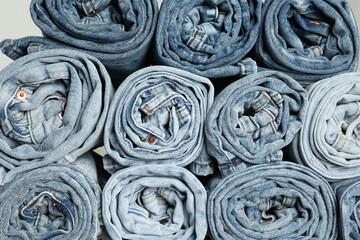Different stylish rolled jeans as background, top view