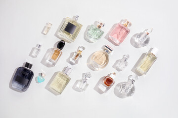 Bottles of various perfumes on light background, flat lay