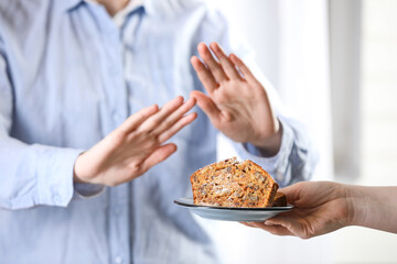 Woman refusing carrot cake indoors, selective focus. Food allergy concept