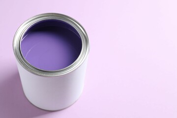 Can of bright paint on violet background, closeup. Space for text