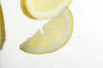 Soda water with lemon slices as background, closeup
