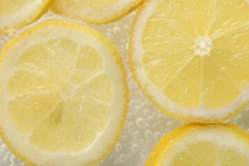Soda water with lemon slices as background, closeup