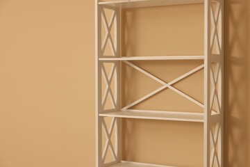 Empty shelving unit near beige wall indoors, closeup. Space for text