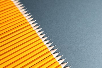 Many graphite pencils on grey background, above view. Space for text