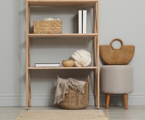 Wooden shelving unit with different home decor near light grey wall indoors