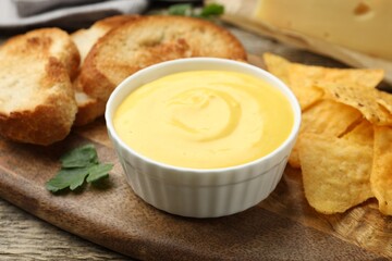Tasty cheese dipping sauce in bowl and snacks on table, closeup