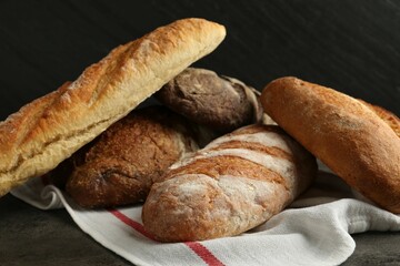 Different types of fresh bread on dark textured table, closeup