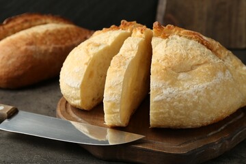 Different types of fresh bread and knife on dark textured table, closeup