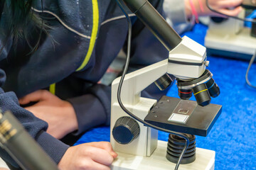 a person looks through a microscope at bacteria. standing microscopes at a science fair. a device for observing small objects with great magnification. microresearch