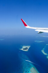 Scenery view of Maldives islands top view from airplane wing flying in the blue sky above Maldives...
