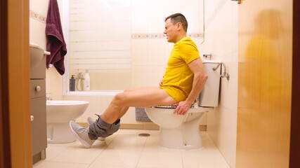Man suffering from stomach ache sitting on toilet