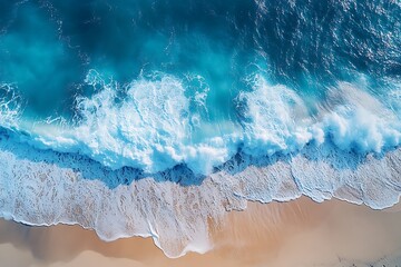 Fototapeta premium Aerial View, Blue Ocean Waves Crashing on Sandy Shoreline, Natural Light, Scenic