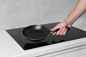 Chef holding frying pan over cooktop in kitchen, closeup