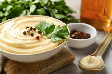 Delicious mayonnaise sauce with parsley and peppercorns in bowl on table, closeup
