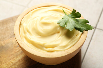 Delicious mayonnaise sauce with parsley in bowl on tiled table, closeup